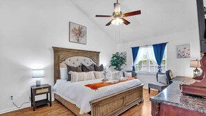 A bedroom with a bed, bedside table, lamp, ceiling fan, window with curtains, and a desk with a chair. - Updated University Area Home with Hot Tub Near Charlotte Your Perfect Retreat! (Charlotte)