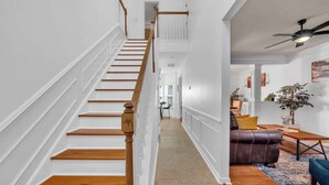 A staircase with wooden steps and white walls, leading to a living area with a sofa and a coffee table. - Updated University Area Home with Hot Tub Near Charlotte Your Perfect Retreat! (Charlotte)