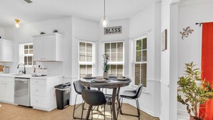 A modern kitchen with white cabinetry, a dining table with chairs, and a sign that reads 'BLES.' - Updated University Area Home with Hot Tub Near Charlotte Your Perfect Retreat! (Charlotte)