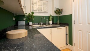 Een moderne keuken met een marmeren aanrecht, een spoelbak en groene wanden.