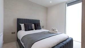 Une chambre moderne avec un grand lit, une tête de lit grise et une vue sur l’extérieur grâce à une porte coulissante.
