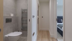 Une salle de bain moderne équipée de toilettes, d’un porte-serviettes et d’un espace douche.