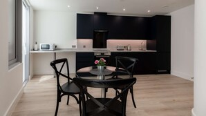 A modern kitchen with dark cabinets, a round dining table, and two chairs. - Modern 1-Bedroom Stay in Stratford near to Canary Wharf | Ideal for Business or Leisure (London)