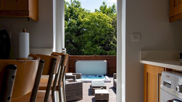 Una cocina con vistas a una terraza exterior, lavadora y mobiliario de mimbre.