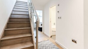 A staircase with wooden steps and a metal railing leading to a room with a white door and a light-colored floor. - Prime Serviced Apartments in Trafalgar Square, London (London)