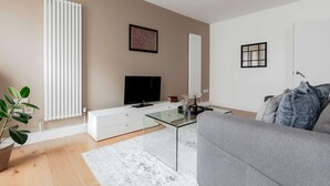 A modern living room with a flat-screen TV, white furniture, and a grey sofa. - Premium Serviced Apartments in Covent Garden (London)
