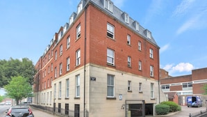 A multi-story red brick building with a beige lower section, likely a residential or mixed-use property. - Pass the Keys | Home & Haven Canterbury (Canterbury)