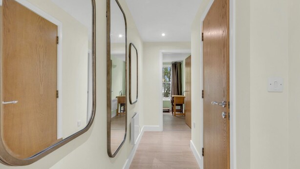 A hallway with wooden doors and mirrors on the walls. - Pass the Keys | Home & Haven Canterbury (Canterbury)