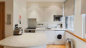 Une cuisine compacte équipée d’un four à micro-ondes, d’un grille-pain, d’un évier et d’un lave-linge.