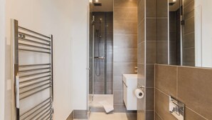 A modern bathroom with a shower, toilet, and a towel rack. - Monument by Excel Apartments, London – Perfect for Short Lets and Corporate Stays (London)
