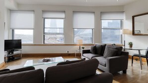A modern living room with a sofa, a coffee table, and a TV. - Monument by Excel Apartments, London – Perfect for Short Lets and Corporate Stays (London)