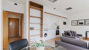 A modern living room with a glass coffee table, a grey sofa, and a wooden door. - Monument by Excel Apartments, London – Perfect for Short Lets and Corporate Stays (London)