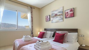 A hotel room with two beds, a large window with a view, and artwork on the walls. - Golfer’s Paradise! Spacious Apt in La Cala Golf | Pass the Keys (Mijas)