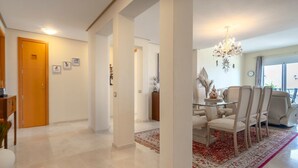 A spacious living area with a dining set, a chandelier, and a view through a large window. - Golfer’s Paradise! Spacious Apt in La Cala Golf | Pass the Keys (Mijas)