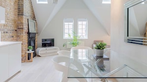 Un loft amplio con techo alto, paredes de ladrillo visto y una cocina moderna.