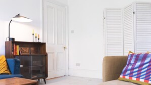 A living room with a sofa, a coffee table, a bookshelf, and a lamp.