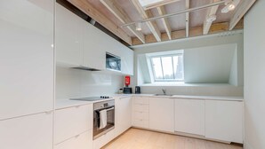 Una cocina moderna con armarios blancos, horno empotrado y ventana sobre el lavamanos.