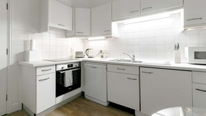 A modern kitchen with white cabinets, a built-in oven, a microwave, and a sink. - Luxurious Serviced Apartments in the Heart of Marylebone, London (London)