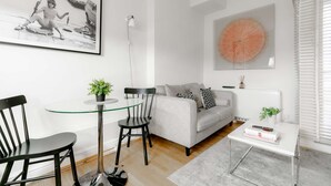 A modern living room with a grey sofa, black and white patterned pillows, a glass coffee table, and a black metal chair. - Luxurious Serviced Apartments in the Heart of Marylebone, London (London)