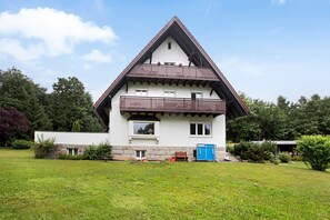 Eine zweistöckige Chalet mit Balkon, Steinmauerwerk und einem gepflegten Rasen.