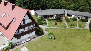 Un bâtiment à deux étages, doté d’un toit rouge, d’un balcon et d’un jardin.