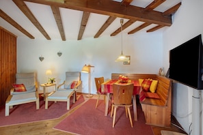 Ein gemütliches Zimmer mit Holzmöbeln, einem Esstisch und einem Fernseher.
