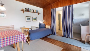 Une pièce confortable avec un lit, une table, une chaise, une étagère remplie de livres et une vue sur une salle de bain.