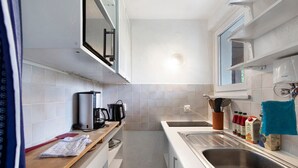 Une cuisine compacte équipée d’une machine à café intégrée, d’un évier et d’une fenêtre.