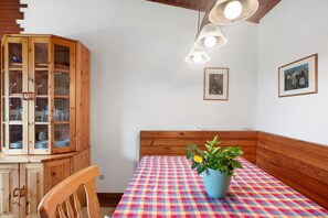 A dining area with a checkered tablecloth, wooden cabinetry, and a potted plant.