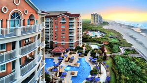 A hotel with multiple floors, a rooftop pool, and a view of the beach.