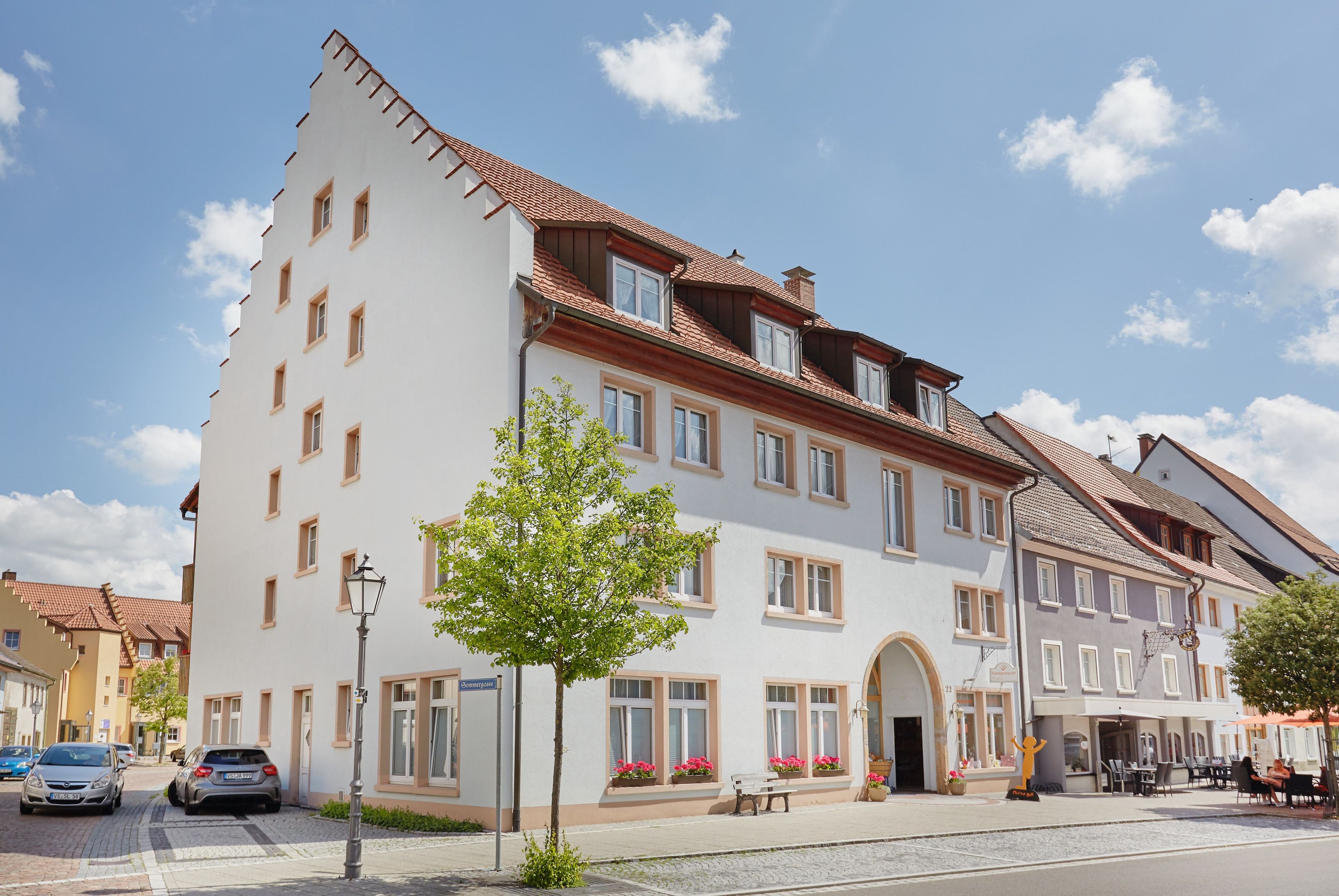 Ein mehrgeschossiges Gebäude mit heller Fassade, zahlreichen Fenstern und einem roten Ziegeldach.
