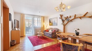 A living room with a sofa, a dining table, a TV, and a red rug. - Apartment 'Südschwarzwald' with Balcony and Wi-Fi (Bräunlingen)