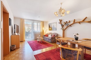 A living room with a sofa, a dining table, a TV, and a red rug. - Apartment 'Südschwarzwald' with Balcony and Wi-Fi (Bräunlingen)
