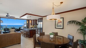 A spacious living area with a dining table, wicker chairs, and a large potted plant.