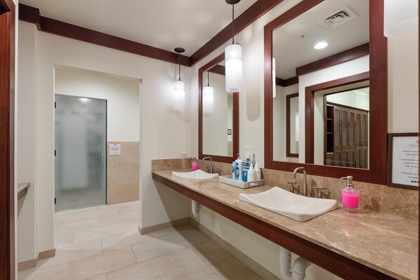 A hotel bathroom with two sinks, a mirror, a towel rack, and a door.
