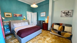 Une chambre à coucher comprenant un lit, un canapé, une table de chevet et un mur orné de tableaux encadrés.