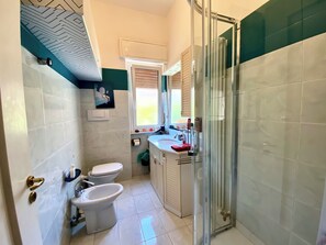 Un baño con inodoro, bidé y ducha.