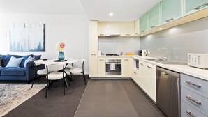 A modern kitchen with white cabinets, a dishwasher, and a built-in oven. - Beaufort Street 1bdr Parking (Perth)