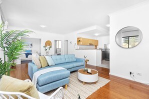 Ein modernes Wohnzimmer mit einem blauen Sofa, einem runden Couchtisch und einem großen Spiegel an der Wand.