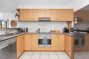 Une cuisine moderne avec des meubles en bois, une cuisinière en acier inoxydable et un lave-vaisselle.