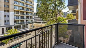 A high-rise building with multiple balconies, a tree in the foreground, and a clear sky. - Stunning 1bdr Paradise - Gym Pool (Perth)