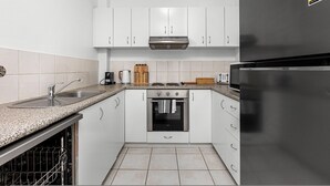 A modern kitchen with white cabinets, a stainless steel refrigerator, a built-in oven, and a dishwasher. - Stunning 1bdr Paradise - Gym Pool (Perth)