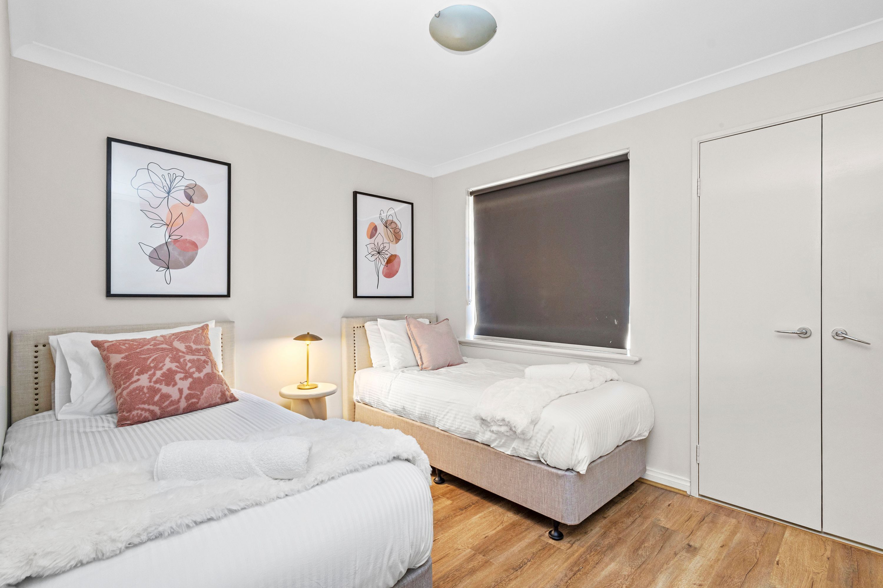 A bedroom with two beds, a wardrobe, and artwork on the walls.