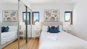 A modern hotel room with a large bed, two bedside tables, a mirror, and artwork on the walls. - 1bdr Parking on Beaufort Street (Perth)