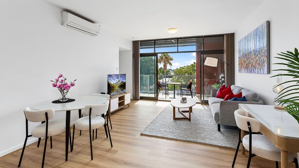 A modern living room with a dining area, large windows, and a view of the outdoors. - 1bdr Parking on Beaufort Street (Perth)
