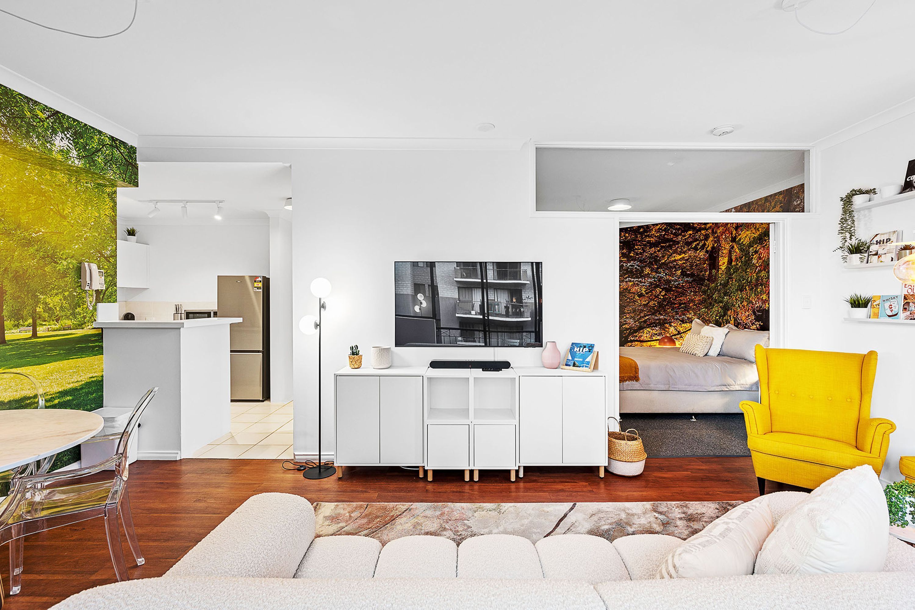 A modern living space with a kitchen, dining area, and a cozy seating area with a yellow armchair.