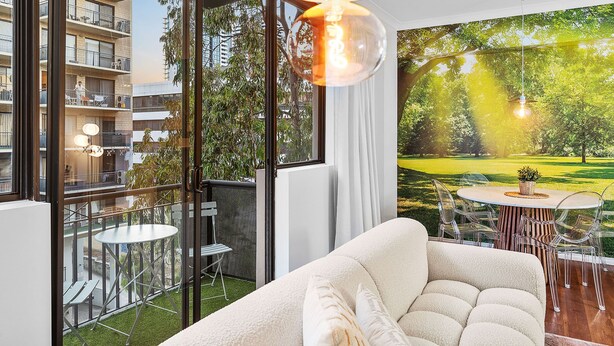 A modern living room with a large window, a sofa, a dining table with chairs, and a hanging light fixture. - Bespoke East Perth - Sleeps 2 - Superior Wifi (Perth)