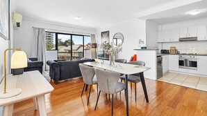 A modern kitchen with white cabinets, a built-in oven, and a dishwasher. - Modern 2BR Pool Gym Parking (Perth)