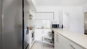 A modern kitchen with stainless steel appliances, white cabinetry, and a dishwasher. - Perfect Location 2BR 1bth - Beckenham (Perth)