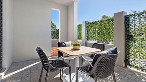 A patio with a table and four chairs, a potted plant, and a view of greenery. - Perfect Location 2BR 1bth - Beckenham (Perth)